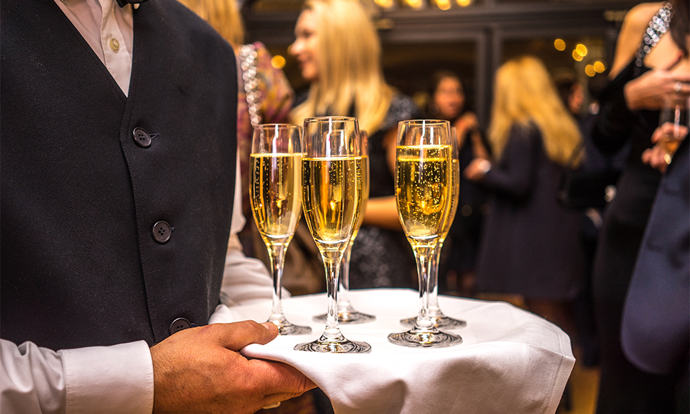 Cameriere serve bicchieri con spumante per brindisi