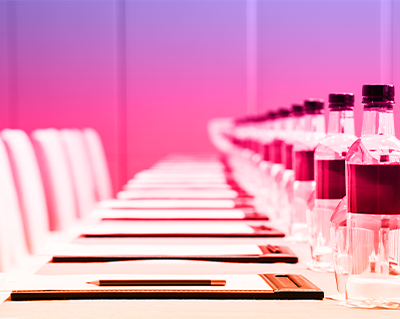 Sala convegno allestita da bottiglie d'acqua e block notes per invitati