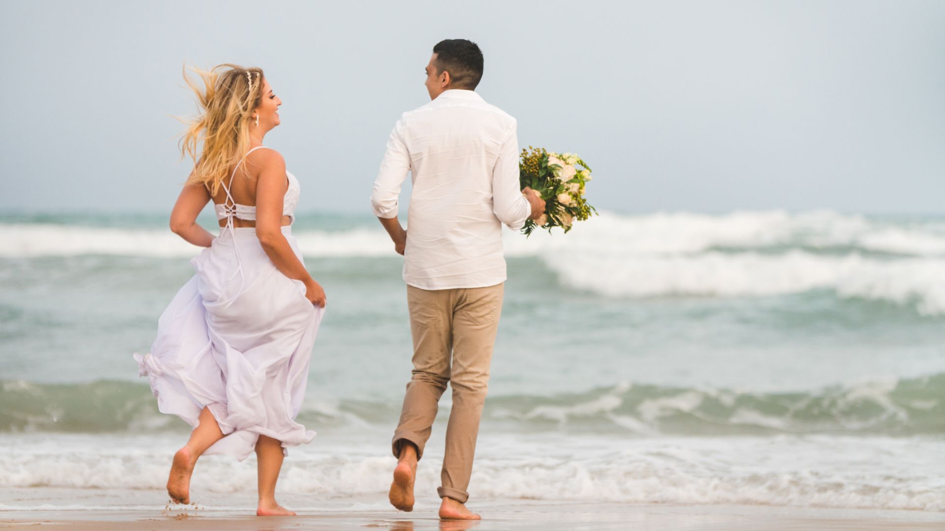 sposi che corrono sulla spiaggia